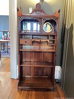 Full front view showing entire cabinet, carvings, mirrors, shelves, drawer