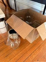 Box with multiple clear glass vases and three vases set outside