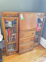 Front view showing full oak cabinet with glass doors, drop-front, drawers