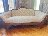 Front view of carved wooden frame sofa with beige floral upholstery