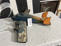 Left side view of wooden Halifax Bomber model showing blue fuselage, orange tail fins, three visible propellers, paint wear