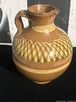 Full view of brown glazed jug showing spout, handle, decorative bands