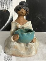 Front view of seated Pamela figurine holding turquoise bowl