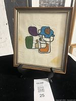 Full view of framed embroidered abstract textile art on stand with lot card