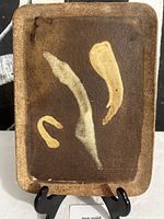 Front view of stoneware tray showing abstract cream slip design and overall form