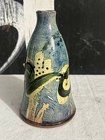 Front view of glazed stoneware oil cruet showing painted design and form