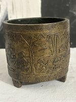 Side view showing raised relief decoration and tripod feet