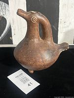 Left perspective showing bird form, handle, spout, tripod foot