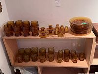 Full lot on two-tier shelf showing tumblers, plates, candleholders, shakers and covered jar