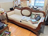 Full frontal view of carved settee showing upholstery and scrollwork