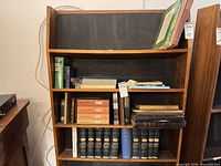 Overall view of bookshelf showing multiple antique/vintage books including matched blue set and various titles