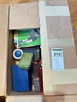 Cardboard box containing tins, instruction booklet and loose perforated plates
