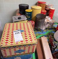 Assorted tins, sifter, stoneware jars, mugs grouped on table