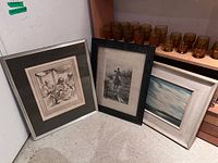 Three framed artworks leaning together showing relative sizes and frames
