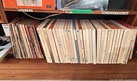 Row of boxed reel-to-reel tapes with handwritten labels on shelf