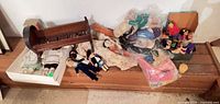 Wide view of cradle, boxed Inuit dolls, pile of assorted dolls and clothes