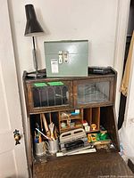 Overall view showing lamp on top of desk, green lock box, punch, stapler, and pencil cups