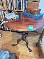 Full view of round mahogany tilt-top table with items on top for scale