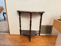 Full view of two-tier demi-lune side table against wall