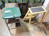 Two metal step stools side by side on floor