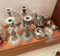 Group shot showing four candlesticks, teapot, creamer, sugar bowl, shallow dish and trivet