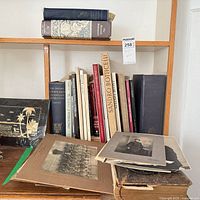 Full view of shelf with stack of photographs and lineup of hardcover books