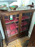 Front view of bookcase showing two glass doors, red felt interior shelves, and key in lock