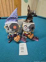 Both Funko Ruin plush dolls on pool table with tags