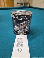 Front view showing sealed cylindrical package, car inside, Hot Wheels logo, 1 of 15,000 note