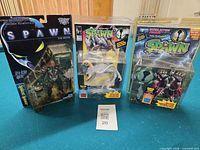 Three sealed Spawn action figures grouped: Spawn The Movie, Medieval Spawn, Violator