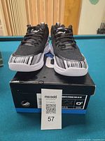 Front view of sneakers on box showing toe design and size card