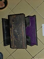 Top view of black metal card holder showing worn finish and purple felt interior