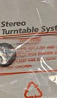 Close-up of plastic-wrapped warning sheet labelled Stereo Turntable System