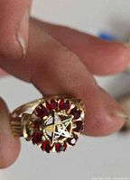 Ring held between fingers showing emblem and stones