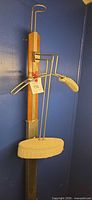 Full view of valet stand showing wood post, metal hanger, hat loop, pad