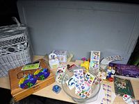 Overview of lot on tabletop showing cigar box, wicker basket, stickers, trinket box, Xena book, shot glasses, toys