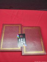 Two closed red binders with gold trim