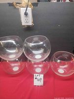 Five clear glass bubble bowls grouped on red surface