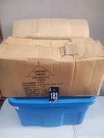 Sealed cardboard case on blue tote containing stones