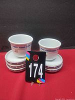 Six white ceramic bowls with blue Greek key border and red Chinese character, four stacked with two on top
