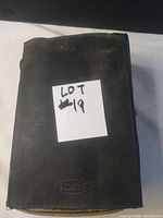 Closed brown leatherette case marked with lot label