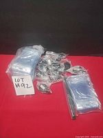 Group of sealed clear badge holders and multiple bagged retractable reels on red surface