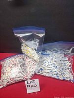 Three zip bags filled with white wooden golf tees with red, yellow, and blue stripes
