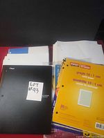 Group shot showing black notebook, Baseline refill pack, Staples graph pack, loose paper