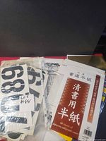 Stack showing calligraphy paper pack, vinyl numbers, rub-on lettering sheets