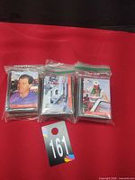 Three zip-top bags of trading cards on red surface, top cards Mark Oswald, race car, Tom Roberts