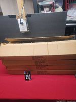 Four long sealed cartons stacked on table