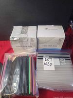 Overall lot showing two boxes of paper straws and two bags of plastic straws