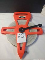 Front view showing red open-reel frame, crank handle and brand badge