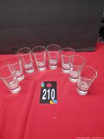 front view of 8 clear tall shot glasses arranged in semicircle